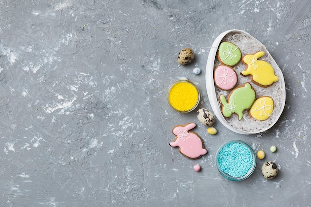 Galletas de Pascua coloridas en cesta con huevos de Pascua de varios colores sobre fondo de color Concepto de vacaciones de huevos de Pascua de color pastel con espacio de copia