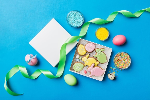 Galletas de Pascua coloridas en cesta con huevos de Pascua de varios colores sobre fondo de color Concepto de vacaciones de huevos de Pascua de color pastel con espacio de copia