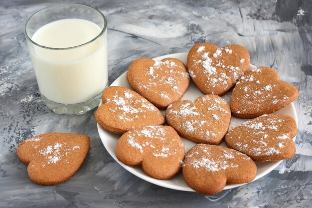 galletas en plato blanco y fondo gris y vaso de leche