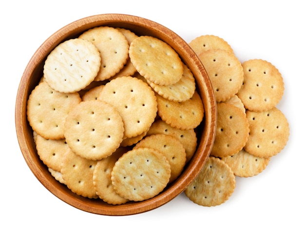 Galletas en un plato de madera y esparcidas en una vista superior de fondo blanco