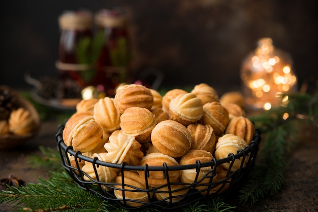 Galletas de postre navideño con nueces con leche condensada hervida en una pared oscura con guirnaldas y decoraciones navideñas