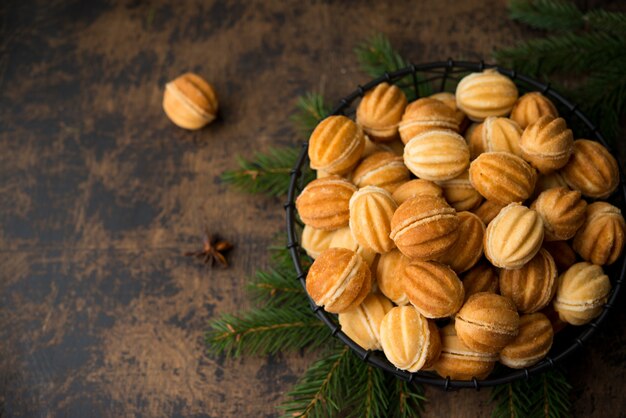 Galletas de postre navideño con nueces con leche condensada hervida en una pared oscura con guirnaldas y decoraciones navideñas