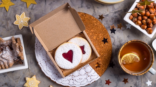 Galletas redondas con mermelada en forma de corazón en una caja de regalo entre adornos navideños