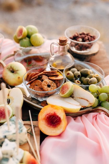 Galletas redondas en un recipiente sobre una mesa con aceitunas verdes una botella de aceite de oliva y frutas