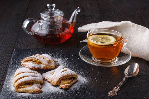 Galletas de requesón con manzana en un plato con té en la mesa de madera oscura