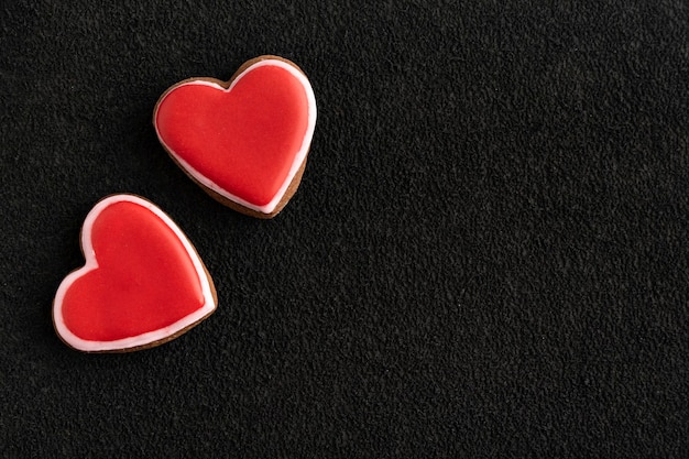 Galletas rojas en forma de corazones sobre fondo negro. Delicia del día de San Valentín.