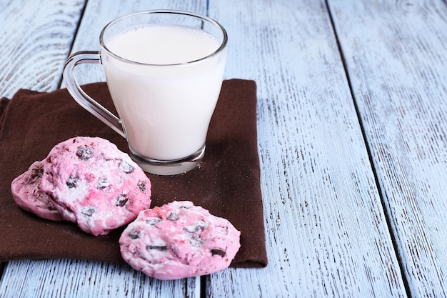 Galletas rosas y taza con leche en primer plano de la mesa