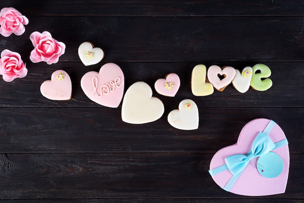 Galletas de San Valentín en forma de corazón sobre fondo de madera oscuro