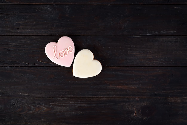 Galletas de San Valentín en forma de corazón sobre fondo de madera oscuro