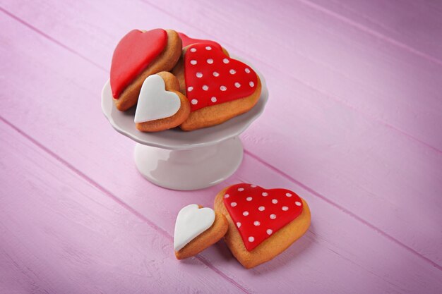 Galletas de san valentín en stand contra fondo de madera