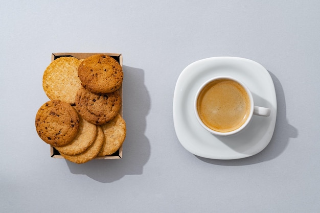 Galletas y taza de café sobre fondo gris