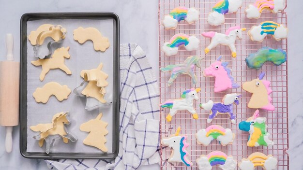 Galletas de unicornio decoradas con royal icing secándose en tendedero.