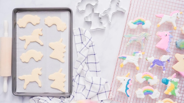 Galletas de unicornio decoradas con royal icing secándose en tendedero.