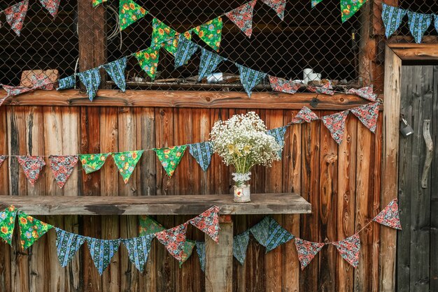 Foto galpão de madeira decorado com bandeiras coloridas e buquê de flores brancas