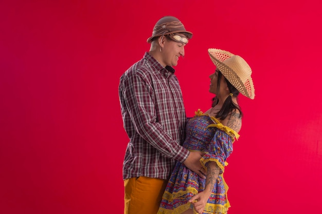 Gama Distrito Federal Brasil 29 de maio de 2022 Jovem casal vestindo trajes festivos em foto de estúdio com fundo vermelho e poses divertidas Festa Junina Brasil