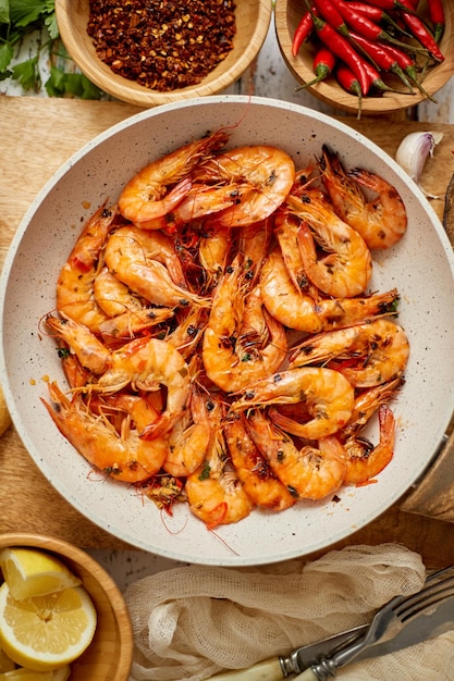 Gambas asadas en sartén servidas en tabla de cortar de madera blanca Fondo de madera oxidada Concepto de almuerzo o cena de mariscos Vista superior plana