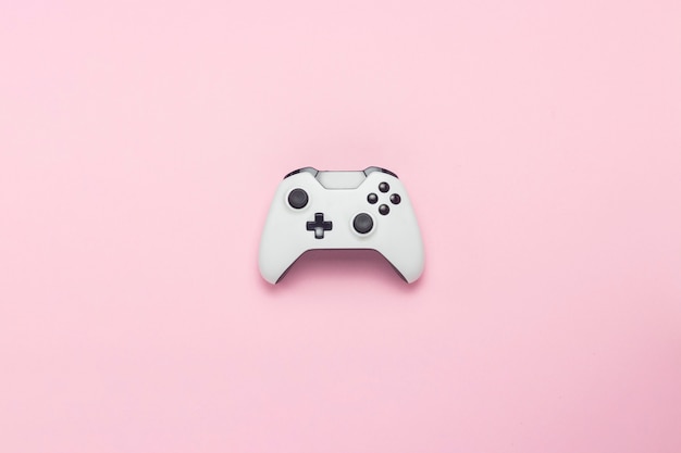 Foto gamepad blanco sobre un fondo rosa. juego conceptual en la consola, juegos de computadora. vista plana, vista superior.