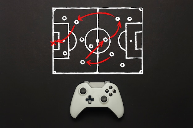 Gamepad branco sobre um fundo preto. adicionado um esquema de campo de futebol. táticas do jogo. jogo do conceito de futebol no console, jogos de computador. vista plana leiga, superior.