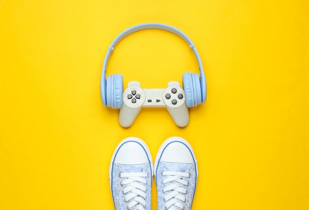 Gamepad com fones de ouvido, tênis em fundo amarelo