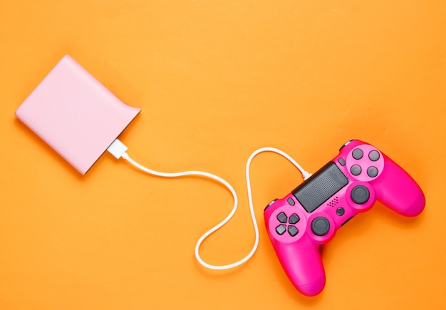 Gamepad de plástico rosa moderno carregando do banco de energia