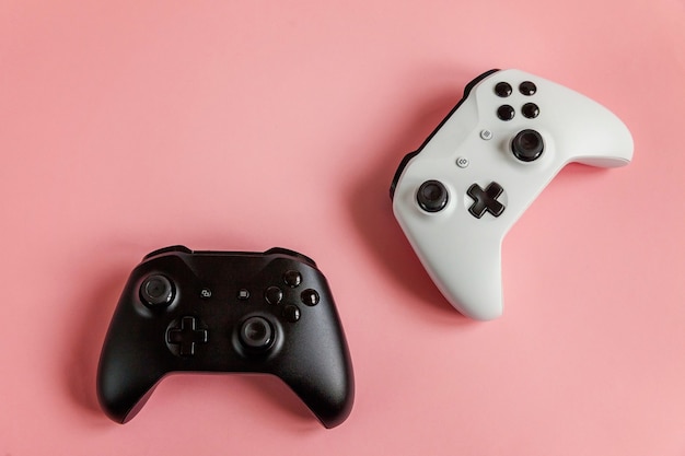 Gamepad de dos joysticks blanco y negro, consola de juegos sobre fondo rosa pastel colorido pin-up de moda