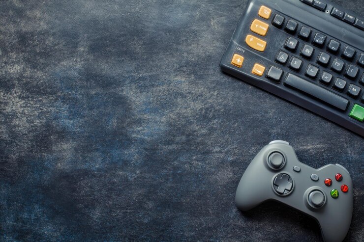 Gamepad gris y teclado negro sobre una superficie de textura grunge oscura con espacio de copia