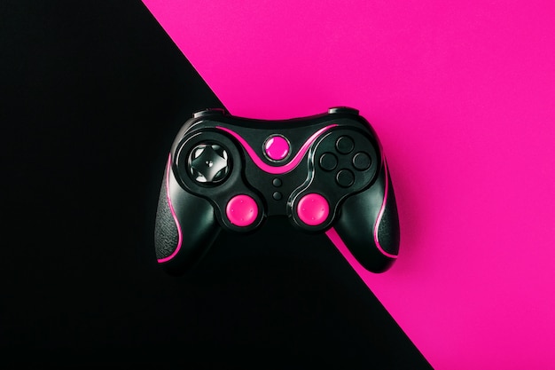 Gamepad negro sobre superficie negra y rosa