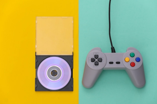 Gamepad retro e CD em fundo amarelo azul. Jogos, competição de videogame. Vista do topo