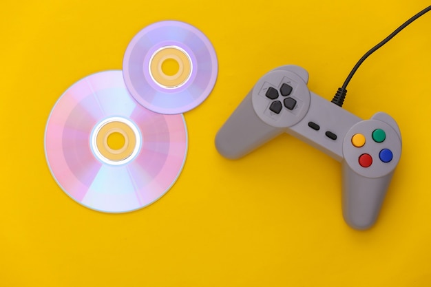 Gamepad retro e CD em fundo amarelo. Jogos, competição de videogame. Vista do topo