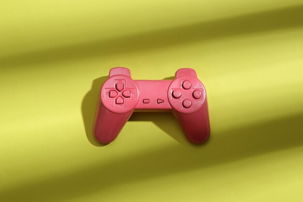 Gamepad rosa em um fundo verde com sombra listrada na moda Arte conceitual de abstração de minimalismo