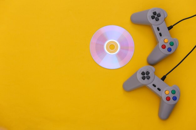 Gamepads retrô, cd's em fundo amarelo. Jogos retrô. Videogame estéreo, anos 80. Vista do topo. Postura plana