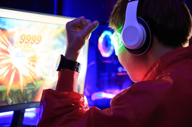 Gamer jugando juegos en línea en PC en una habitación oscura.