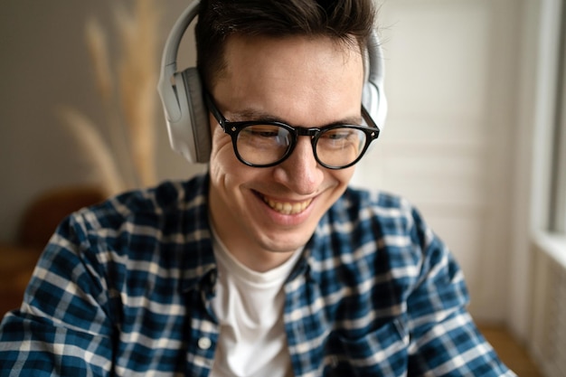 Gamer macho adulto en auriculares inalámbricos y gafas cerrar retrato feliz jugando un juego