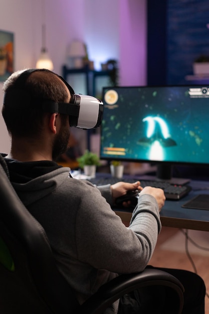 Gamer mit VR-Brille und Controller zum Spielen von Videospielen. Mann mit Virtual-Reality-Brille, der Joystick vor Computer hält und Online-Spiel spielt. Spieler, der Spaß mit Spielen hat.