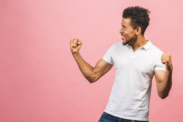¡Ganador afroamericano! Hombre alegre alegre varonil atractivo hermoso, mostrando ganar sí gesto fresco, celebrando, aislado sobre fondo rosa.