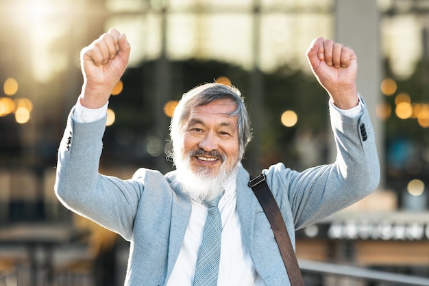 Ganador asiático y éxito empresarial con puño en alto al aire libre para celebrar después de ganar un logro u oportunidad en la ciudad Retrato de empresario chino celebra metas para motivación al aire libre