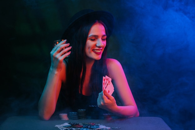 El ganador de la chica afortunada juega al póquer en la mesa con fichas y cartas en el casino