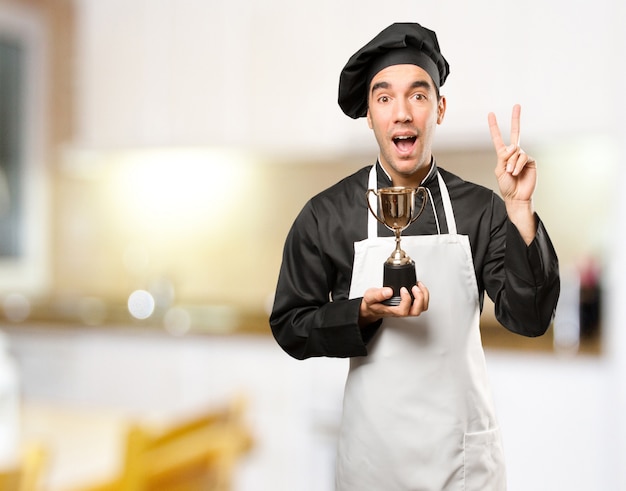 Ganador joven chef sosteniendo una taza de oro