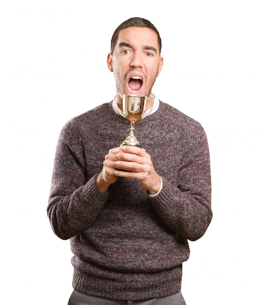 Foto ganador joven sosteniendo una taza de oro