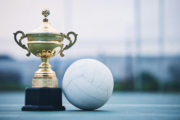 Ganador de oro y deportes con trofeo y netball por logro y campeonato Celebración de fitness y victoria con premio y pelota en el terreno de la cancha para competencia de eventos y éxito