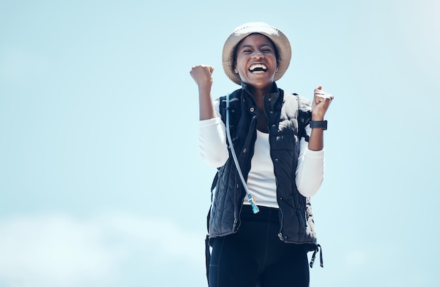 La ganadora feliz y la mujer negra celebran el viaje de fitness en la naturaleza en la victoria de la caminata durante la aventura Éxito cielo azul y viajes risa y libertad salud sin preocupaciones y estilo de vida activo