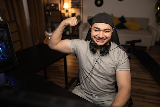 Ganando la ronda en un videojuego de computadora, un hombre barbudo con auriculares disfruta de la alegría de la victoria