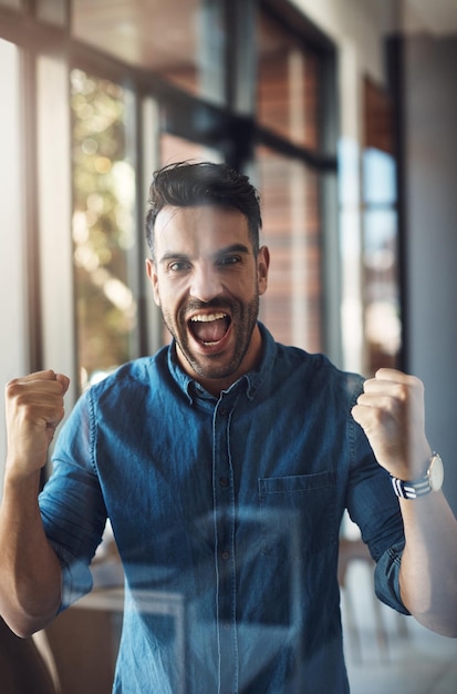 Foto ganar celebrando y animando a un joven empresario exitoso feliz por el éxito en su negocio retrato de un propietario emocionado y nuevo que se siente alegre y positivo por su empresa