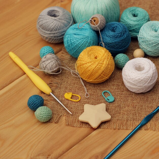 Ganchos de crochet amarillos y azules y bolas de hilo de algodón sobre una mesa de madera, copie el espacio.