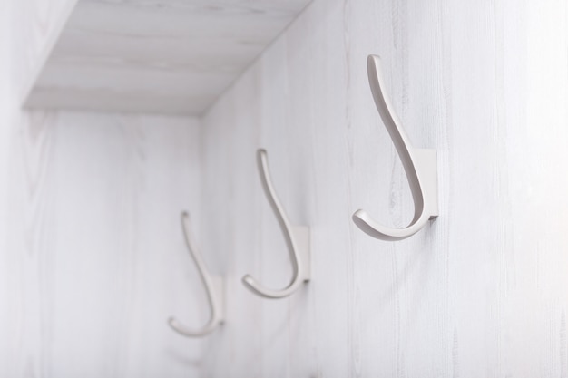 Ganchos vacíos de pared sobre tablero de madera blanca.