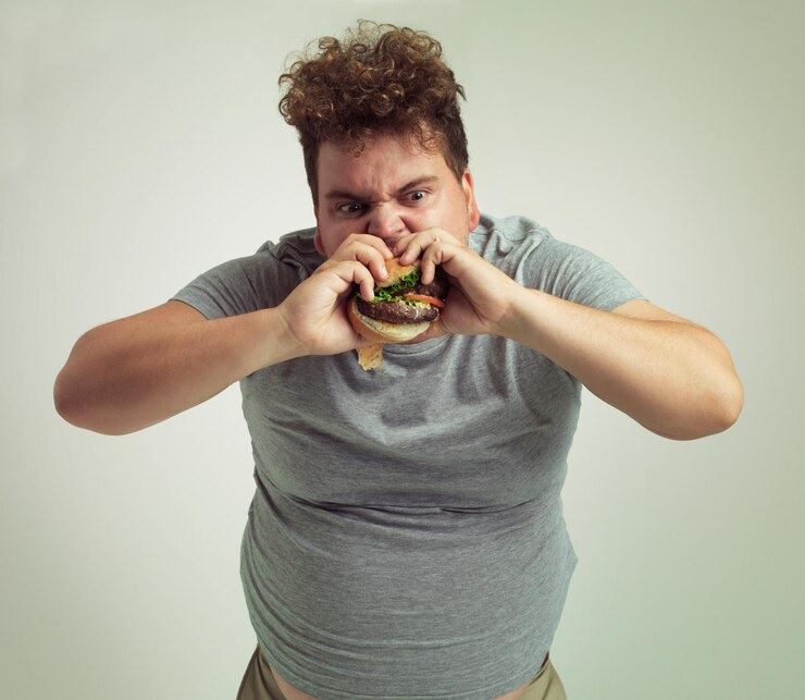 Foto ganho de peso takeaway e hambúrguer para o homem no estúdio com fastfood para comer não saudável mais tamanho e ganância jovem com refeição na boca e estômago gordo para a fome carne e molho para morder interior
