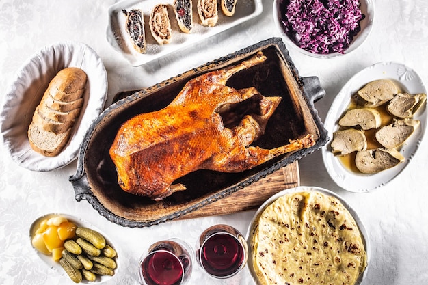 Ganso asado con guarniciones Strudel de repollo rojo albóndigas de patata encurtidos pan y vino tinto