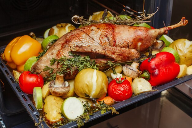 Ganso relleno asado entero con manzanas, hierbas y verduras