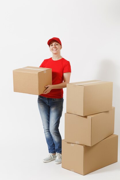 Ganzaufnahme der Lieferfrau in roter Mütze, T-Shirt, das die Bestellkästen einzeln auf weißem Hintergrund gibt. Weiblicher Kurier in der Nähe von leeren Kartons. Paket empfangen. Kopieren Sie Platz für Werbung.