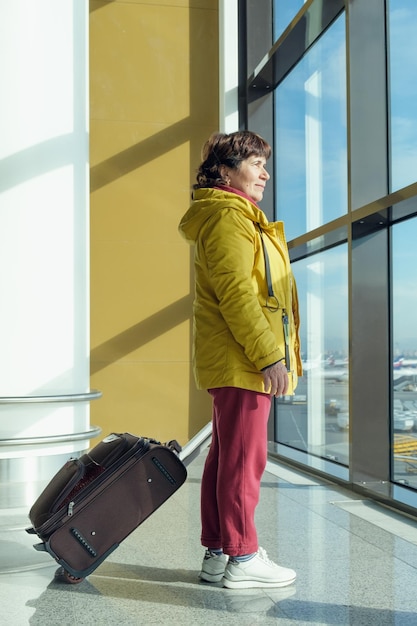 Ganzaufnahme einer älteren Frau mit einem Koffer